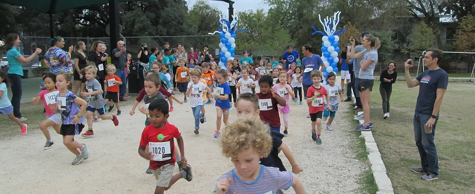 Photo of students running on the track, and being cheered on by their family and teachers